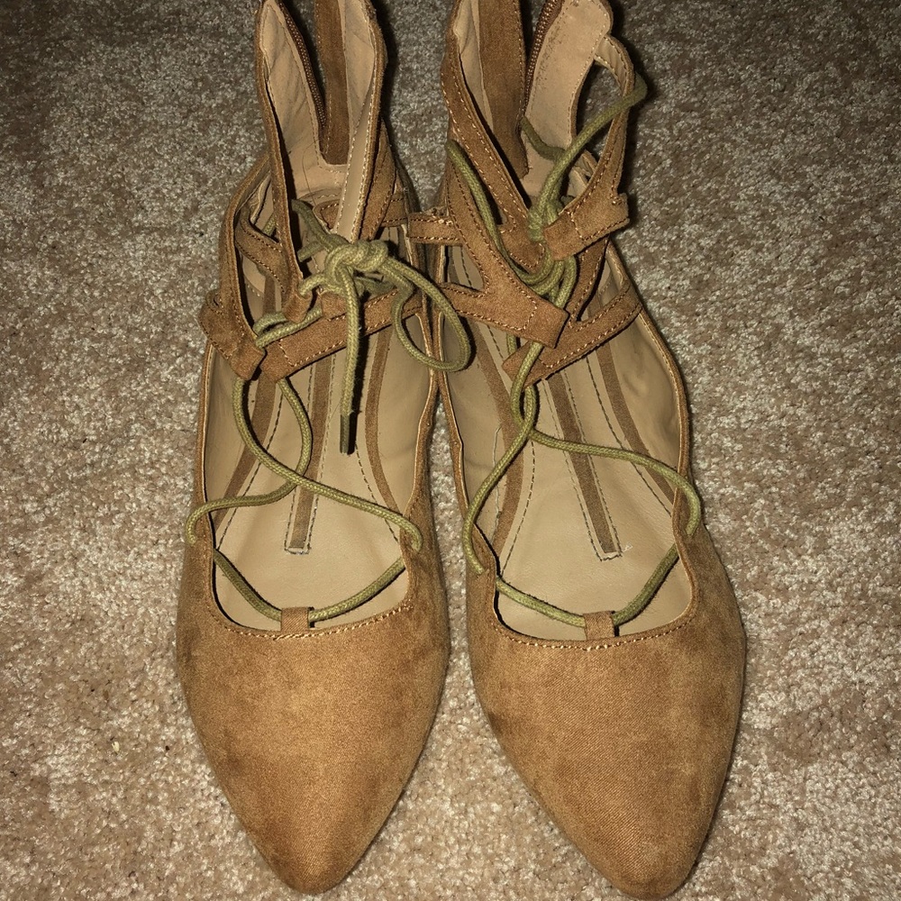 A cute pair of flat, laced up tan sandals!